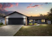 Charming single-story home with a two-car garage and manicured front lawn against a vibrant sunset backdrop at 15690 Sw 46Th Cir, Ocala, FL 34473