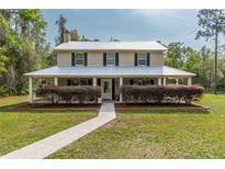 Charming two-story home with a long porch, metal roof, well-maintained landscaping, and a welcoming walkway at 3333 Se 3Rd Ave, Ocala, FL 34471