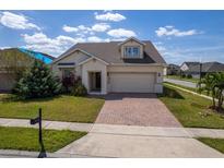 Charming home with a two-car garage and a brick paved driveway, complimented by a green lawn and mature landscaping at 1720 Reflection Ln, St Cloud, FL 34771