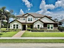 Beautiful two-story home with a manicured lawn, stone accents, and a tile roof under a sunny sky at 7443 Lake Albert Dr, Windermere, FL 34786