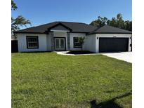 Charming single story home featuring a manicured lawn, gray and white exterior paint, and a black asphalt shingle roof at 8456 Se 164Th Pl, Summerfield, FL 34491