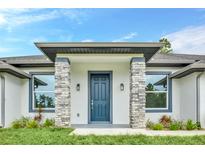 Inviting front entrance with stone pillar accents and a modern, dark blue door under a covered porch at 19073 Sabal St, Orlando, FL 32833