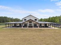 Sprawling, modern farmhouse features a long covered porch, metal roof and ample land at 11657 Moore Rd, Lakeland, FL 33809