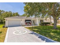 Charming single-story home featuring a well-manicured lawn, a decorative driveway, and a cozy front porch seating area at 2382 Due West Dr, The Villages, FL 32162