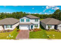 Beautiful two-story home with brick driveway, manicured lawn, and vibrant blue shutters at 3153 Legends Preserve Dr, Daytona Beach, FL 32124