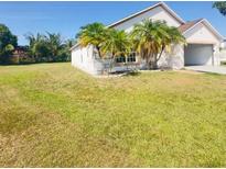 Home exterior featuring a lawn, attached garage, and palm trees at 323 Miami Ln, Kissimmee, FL 34759