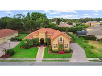 Stunning house featuring a red tile roof, stucco exterior, mature landscaping, and a circular driveway at 6567 Eagle Ridge Way, Lakeland, FL 33813