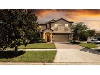 Charming two-story home featuring manicured landscaping and a brick-paved driveway leading to a two-car garage at 1450 Rolling Fairway Dr, Davenport, FL 33896