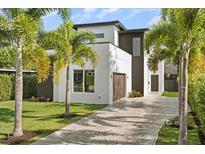 Modern two-story home with meticulously landscaped front yard and paver driveway, surrounded by mature palm trees at 1521 Chestnut Ave, Winter Park, FL 32789