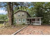 Charming two-story home with a welcoming front porch and brick driveway surrounded by lush greenery at 2508 Yale Ave, Sanford, FL 32773