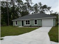 Charming single-story home featuring a well-manicured lawn, attached garage, and a classic, welcoming facade at 24202 Nw Aspen Ln, Dunnellon, FL 34432