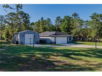 Charming home featuring an extra building, beautiful lawn, and long driveway at 9085 Sw 202Nd Avenue Rd, Dunnellon, FL 34431