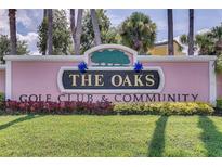 Entrance sign to 'The Oaks' Golf Club and Community with manicured lawn and colorful landscaping at 2960 Boating Blvd, Kissimmee, FL 34746