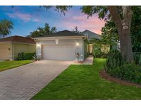 Charming home boasts a brick driveway, attached garage, and inviting curb appeal with mature landscaping at 777 Summit Greens Blvd, Clermont, FL 34711