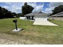 Charming home featuring a well-manicured lawn, a two-car garage and mailbox at 10470 Sw 132Nd Ct, Dunnellon, FL 34432