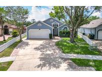 Charming blue house with a well-manicured lawn, mature trees and a two-car garage at 2641 Delcrest Dr, Orlando, FL 32817