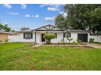 Charming single-story home with a well-maintained lawn and landscaping, set under a partly cloudy sky at 7331 Blue Jacket W Pl, Winter Park, FL 32792