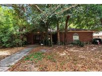 Quaint brick home with mature trees providing shade and curb appeal at 418 W Holly Dr, Orange City, FL 32763