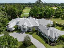 Stunning aerial view of a large luxury home with a patterned driveway and meticulously manicured lawn and gardens at 8707 Nw 31St Lane Rd, Ocala, FL 34482