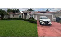 Charming single-story home featuring a well-manicured lawn, red tile roof, and a two-car garage at 440 Bay Leaf Dr, Kissimmee, FL 34759