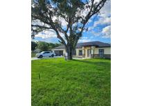 Beautiful single-story home with a lush green lawn and a large tree providing shade at 13074 Sw 104Th Ln, Dunnellon, FL 34432
