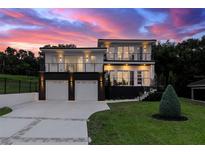 Stunning modern two-story home featuring a two-car garage and a beautifully landscaped front yard at dusk at 1841 Moorings Ct, Clermont, FL 34711