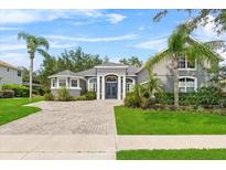 Charming single-story home with a brick driveway, manicured lawn, and lush landscaping at 4013 Greystone Dr, Clermont, FL 34711