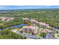 Stunning aerial view of condos with a luxurious community pool surrounded by lush greenery and a peaceful lake at 8601 Worldquest Blvd # 3404, Orlando, FL 32821