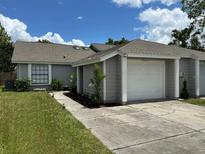 Charming one story home featuring a two car garage, gray siding, and manicured landscaping at 1980 Water Ln, Maitland, FL 32751