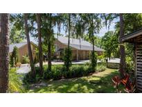Charming home with wood siding, metal roof, lush landscaping, and mature trees providing shade and privacy at 13450 E Lake Mary Jane Rd, Orlando, FL 32832