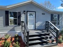 Gray manufactured home with black accents, steps, and landscaping at 9619 Moore Rd, Lakeland, FL 33809