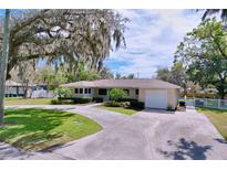 Charming single-story home with a well-manicured lawn, a large tree and a circular driveway at 1025 E Georgia St, Bartow, FL 33830