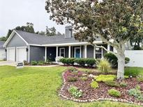 Charming single-story home with a well-manicured lawn, colorful flowerbeds, and a welcoming front porch at 121 Belmont Dr, Winter Haven, FL 33884