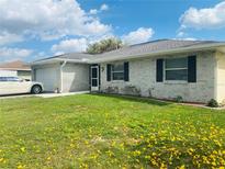 Charming single-story home featuring a white brick exterior, well-maintained lawn and attached garage at 419 Broward Ter, Winter Haven, FL 33884