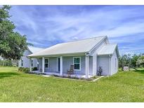 Charming single-story home with a metal roof and inviting front porch, set on a lush lawn at 1040 Timbers Dr, Fort Meade, FL 33841