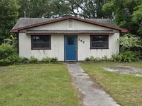 Charming single-story home featuring a blue front door, quaint windows, and a well-maintained lawn at 142 Se Ave B, Winter Haven, FL 33880