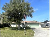 Charming home featuring a well-manicured lawn, an American flag, and an attached two car garage at 4805 Oak Acres Dr, Lake Wales, FL 33898