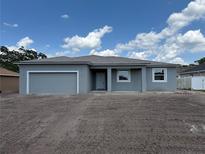 Charming single-story home featuring a grey exterior, attached garage, and a well-manicured front yard under a partly cloudy sky at 498 Big Sioux Ct, Kissimmee, FL 34759