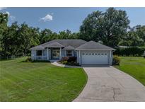Charming single-story home featuring a well-manicured lawn, white picket fence, and an attached two-car garage at 5427 Orange Valley Dr, Lakeland, FL 33813