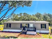 Charming gray home with a manicured lawn, updated windows, and a welcoming front porch at 7005 Dove Meadow Trl, Lakeland, FL 33810