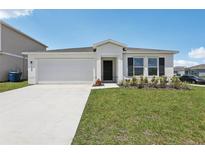 Charming single-story home featuring a two-car garage, well-manicured lawn, and modern architectural details at 3528 Dahlia Dr, Haines City, FL 33844
