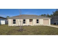 Newly constructed home with a beige exterior and a well-maintained lawn at 405 Manitoba Ln, Poinciana, FL 34759