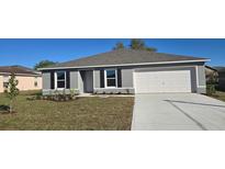 Charming single-story home with gray exterior, landscaped yard, and a two-car garage at 558 Hummingbird Ct, Poinciana, FL 34759