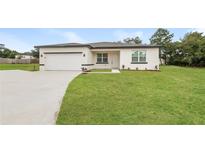 Inviting single-story home features a lush lawn, paved driveway, and attached two car garage at 421 Arkansas Ct, Poinciana, FL 34759