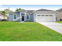 Charming single-story home with a well-manicured lawn and a two-car garage at 13 Haddock Way, Poinciana, FL 34759