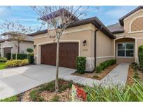 Tan two-story house with brown garage door and landscaping at 3242 Bailey Ann Dr, Ormond Beach, FL 32174