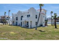 Exterior of a three-story beach house with a Spanish style, manicured lawn, and ocean views at 3072 Ocean Shore Blvd, Ormond Beach, FL 32176