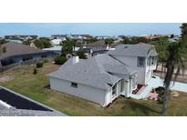 The back of the home features a well manicured lawn, brick border, and the rear elevation of the two-story home at 105 Barrier Isle Dr, Ormond Beach, FL 32176