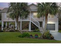 Elevated home with two-story exterior, detached garage, and landscaped yard at 124 Avalon Dr, Ormond Beach, FL 32176