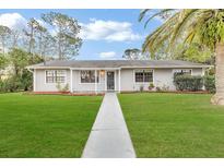 Charming ranch home with a well-manicured lawn and walkway at 89 Hickory Hills Cir, Ormond Beach, FL 32174